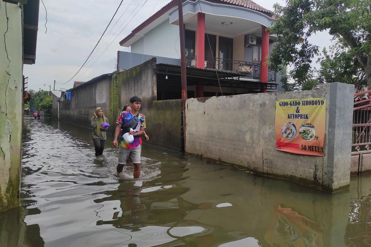 Sejumlah warga Dukuh Kedung Banteng nampak lalu lalang menerjang banjir untuk menengok kondisi rumah, Jumat (23/2/2024). (KOMPAS.COM/NUR ZAIDI)