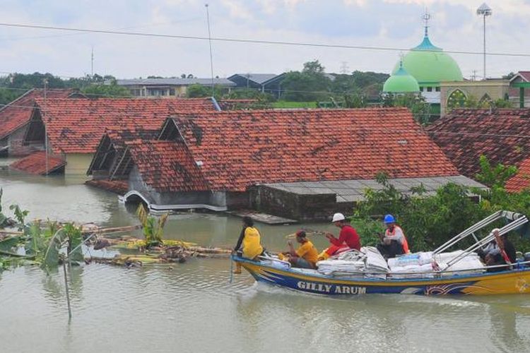 Warga naik perahu di depan rumah yang terendam banjir di Desa Ketanjung, Karanganyar, Demak, Jawa Tengah, Minggu (17/3/2024)