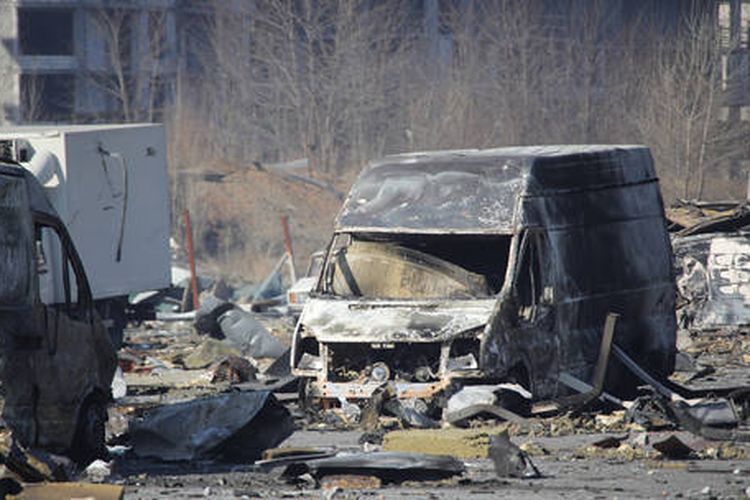 Sebuah van yang terbakar di dekat pusat perbelanjaan yang hancur di Kyiv, Ukraina, Rabu (23/3/2022).
