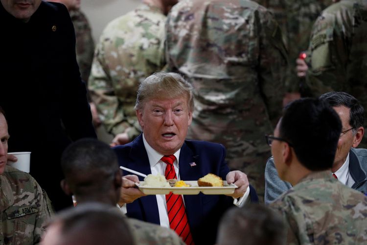 Presiden AS Donald Trump duduk menikmati makan malam bersama dengan pasukan saat berkunjung ke Pangkalan Udara Bagram dekat Kabul, Afghanistan, di tengah perayaan Thanksgiving pada 28 November 2019.