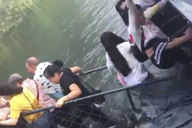 Dalam foto tersebut, terlihat turis yang berada di atas jembatan di Taman Dongjianghu, China, mendapat pertolongan setelah jembatannya ambruk Minggu (12/8/2018).