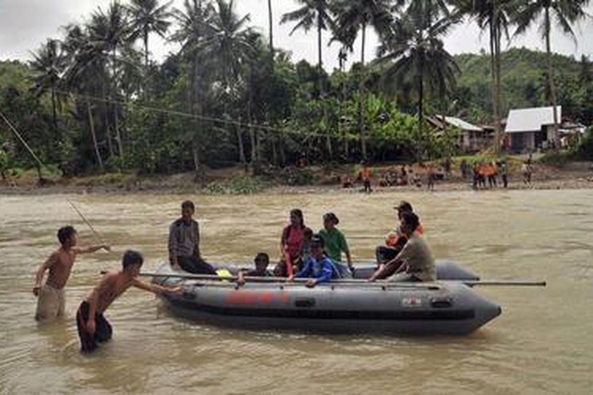 Warga menyeberangi Sungai Susua dengan bantuan perahu karet setelah jembatan sungai tersebut ambruk lantaran diterjang luapan air, Jumat (2/12/2011). Kini pemerintah akan membangun jembatan darurat dengan batang kelapa. 