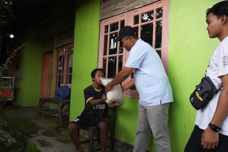 Badarudin, Kepala Desa Talunombo, sedang memberikan bantuan beras kepada warga yang kurang mampu pada Minggu (25/2/2024).