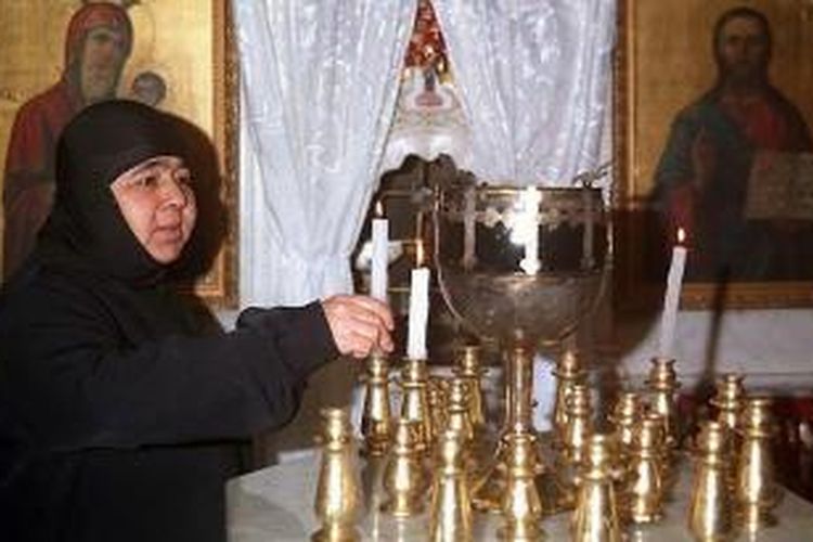 Seorang biarawati Kristen Ortodoks Suriah sedang menyalakan lilin di biara yang terletak di desa Mar Takla, sebelah utara Damaskus, pada 24 Desember 1998. Sebanyak 12 biarawati Ortodoks di kota Maaloula dikabarkan terjebak pertempuran antara pemberontak dan pasukan pemerintah.