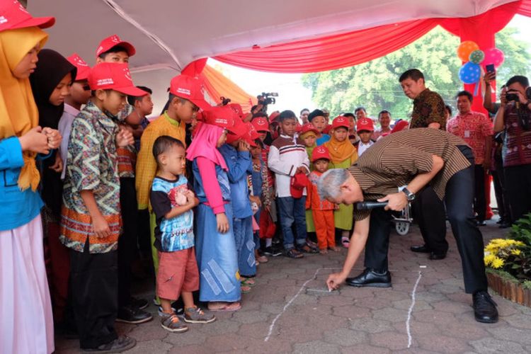 Gubernur Jawa Tengah Ganjar Pranowo tengah asik bermain Englek bersama anak-anak saat peringatan Hari Anak Internasional di Grand Maerakaca, Semarang, Selasa (23/7/2019). 