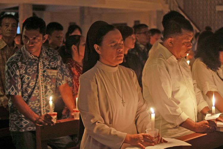 Umat Kristiani menyalakan lilin pada Misa Natal di gereja Santo Kristoforus Kota Gorontalo, Gorontalo, Minggu (24/12/2017). Perayaan Natal yang diikuti ratusan umat Kristiani tersebut mengambil tema Hendaklah Damai Sejahtera Kristus Memerintah Dalam Hatimu.