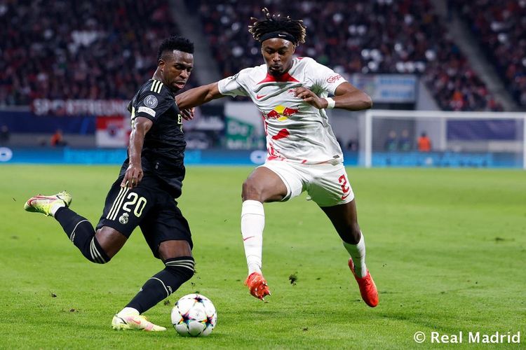 Penyerang Real Madrid, Vinicius Junior (kiri), melepaskan tendangan dan berusaha dihadang pemain RB Leipzig, Mohamed Simakan, dalam pertandingan penyisihan Grup F Liga Champions 2022-23 di Red Bull Arena Leipzig, Selasa (25/10/2022) atau Rabu dini hari WIB.