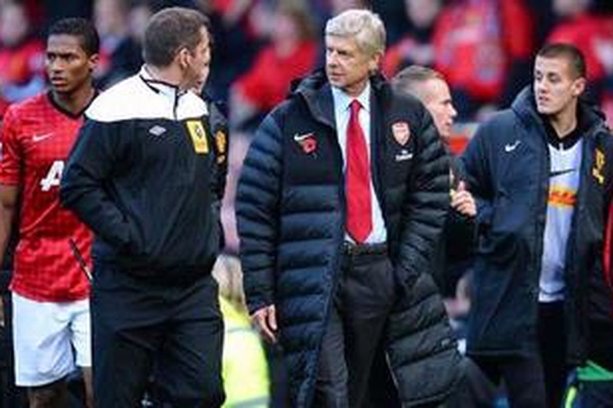 Pelatih Arsenal (kanan), bicara dengan ofisial keempat Phil Dowd, setelah pertandingan Premier League melawan Manchester United (MU), di Old Trafford, Sabtu (3/11/2012), yang dimenangkan MU 2-1. 