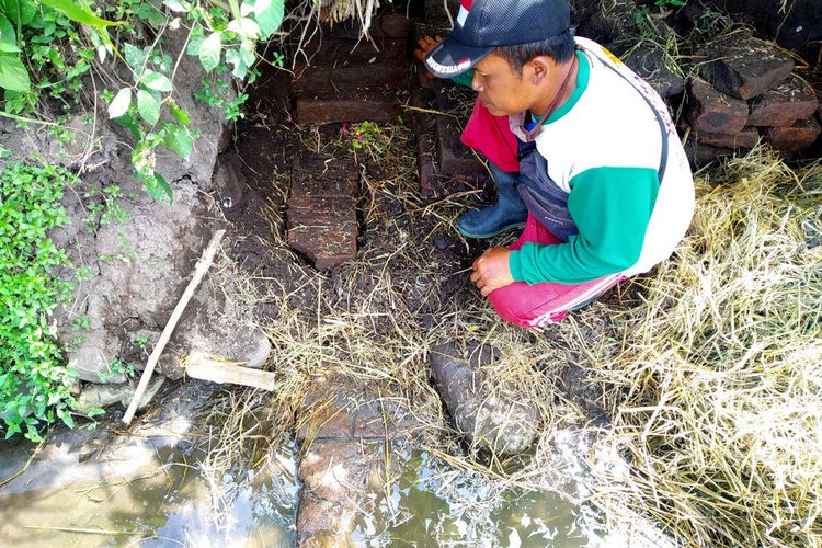 Seorang petani Kelurahan Karangtengah, Kecamatan Sananwetan, Kota Blitar menunjukkan satu bagian dari struktur bangunan diduga bangunan kuno yang terlihat akibat gerusan air saluran irigasi pertanian, Rabu (28/4/2021)