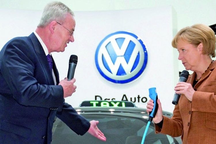 Angela Merkel (kanan) menguji colokan mobil listrik milik VW.