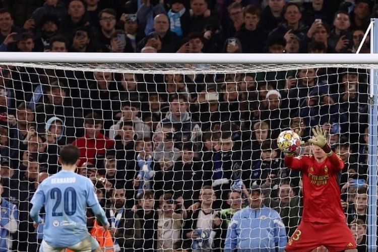 Kiper Real Madrid, Andriy Lunin, menangkap bola dari tendangan penalti gelandang Manchester City, Bernardo Silva, dalam leg kedua perempat final Liga Champions di Stadion Etihad, Rabu (17/4/2024) atau Kamis dini hari WIB.