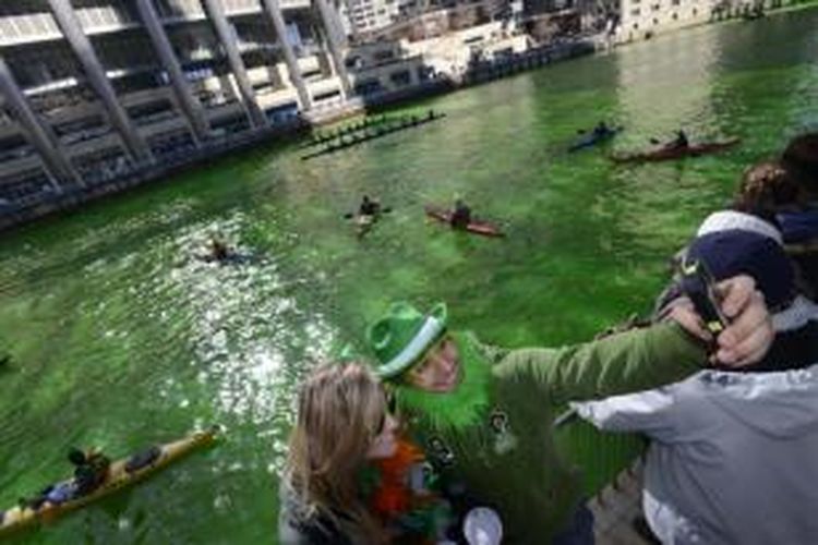 Warga Chicago berfoto di depan Sungai Chicago yang telah diwarnai hijau dalam rangka parade perayaan hari St. Patrick di Chicago, Sabtu (15/3/2014). 