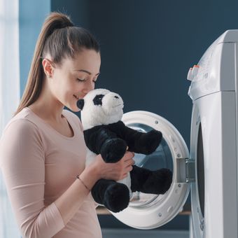 Ilustrasi mencuci mainan boneka dengan mesin cuci.