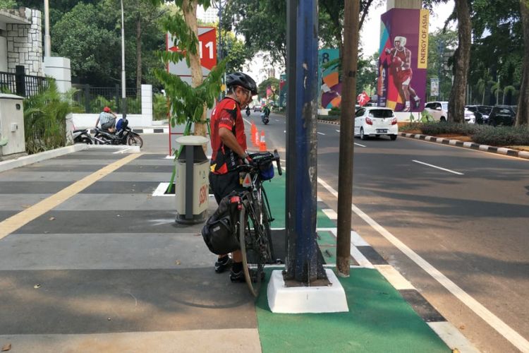 Seorang pesepeda bernama Yupa menyandarkan sepedanya pada tiang yang menghalangi jalur sepeda trotoar Jalan Asia Afrika, Senayan, Jakarta, Selasa (31/7/2018).