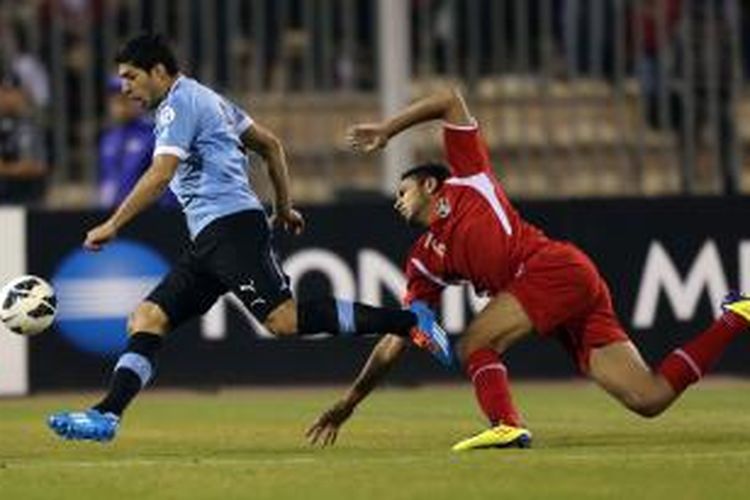 Striker Uruguay, Luis Suarez (kiri), menggiring bola melewati pemain Yordania, Saeed Al-Murjan, dalam pertandingan playoff Piala Dunia 2014 di International Stadium, Amman, Rabu (13/11/2013).