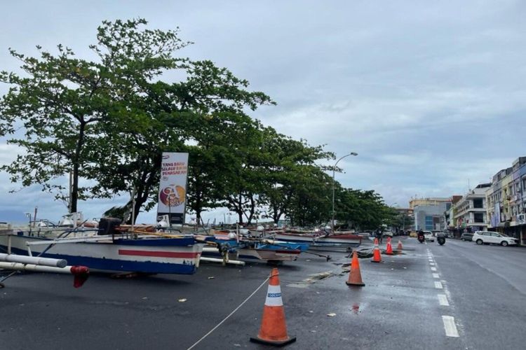 Hindari amukan ombak, perahu nelayan dinaikkan ke darat tepat di badan jalan di Kawasan Megamas, Manado, Sulut, Rabu (8/12/2021). Wilayah bisnis yang ada di lahan reklamasi ini salah satu yang terdampak banjir rob, Selasa (7/12/2021).