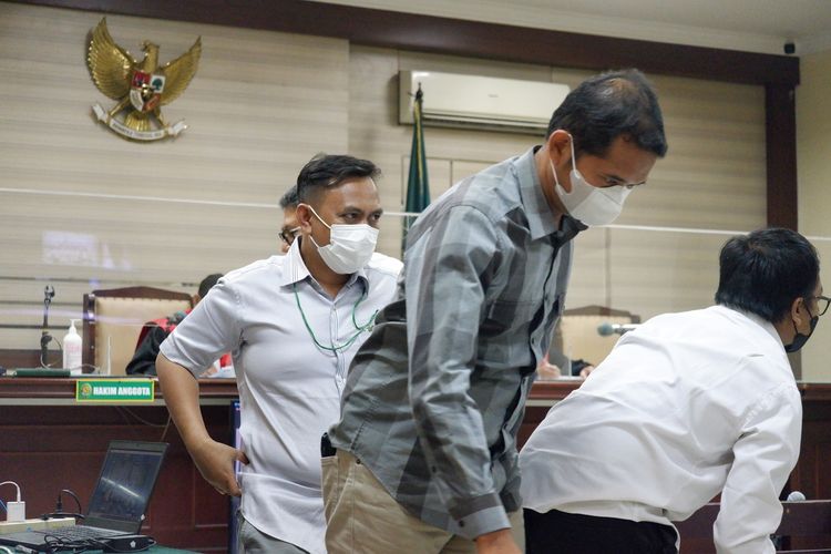 Anggota KPU Bangkalan Sairil Munir (hem pendek) dan Ahmad Ahadiyan Hamid (hem lengan panjang) berjalan meninggalkan ruang sidang usai diperiksa sebagai saksi di Pengadilan Tipikor Surabaya, Jum'at (19/5/2023).