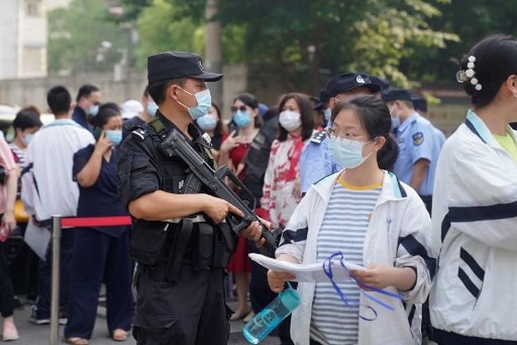 Seorang petugas polisi berjaga ketika siswa tiba untuk hari pertama Ujian Masuk Perguruan Tinggi Nasional (NCEE), yang dikenal sebagai ?gaokao?, di Wuhan, di provinsi Hubei tengah China pada 7 Juni 2022