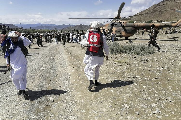 This photograph taken on June 22, 2022 and received as a courtesy of the Afghan government-run Bakhtar News Agency shows soldiers and Afghan Red Crescent Society officials near a helicopter at an earthquake hit area in Afghanistan's Gayan district, Paktika province. - A powerful earthquake struck a remote border region of Afghanistan overnight killing hundreds of people and injuring hundreds more, officials said on June 22, with the toll expected to rise as rescuers dig through collapsed dwellings. (Photo by Bakhtar News Agency / AFP) / XGTY 