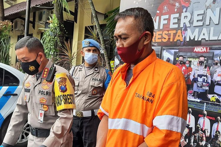 AC (52) terduga pelaku penyebar hoaks Kota Malang zona hitam saat dirilis di Mapolresta Malang Kota, Senin (21/12/2020).