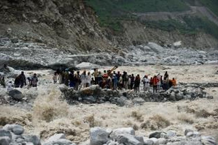 Dalam foto diambil pada 23 Juni 2013 ini terlihat sekelompok peziarah yang terjebak banjir menunggu tim penyelamat di tepian sungai Govind Ghat. Pemerintah Negara Bagian Uttarakhand menyatakan lebih hampir 6.000 orang yang hilang diyakini telah tewas.
