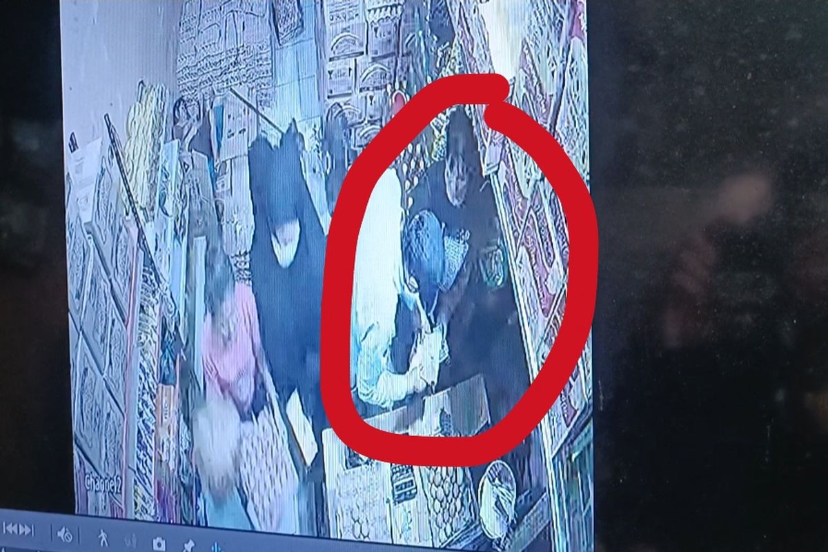 Pelaku penipuan dan pencurian (menggunakan topi) sedang melancarkan aksinya dengan menghipnotis pemilik toko (menggunakan kaos hitam tanpa kerudung) di Jalan Raya Penggilingan, Cakung, Jakarta Timur, Senin (15/5/2023).