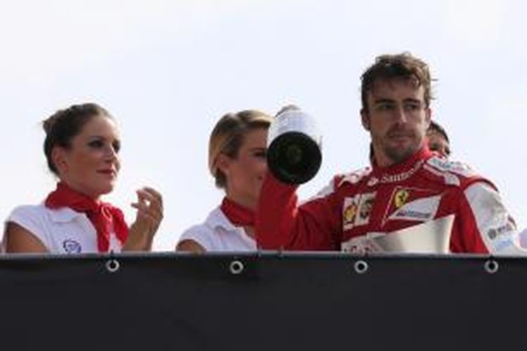 Pebalap Ferrari, asal Spanyol, Fernando Alonso mengacungkan sampagne di podium, saat merayakan suksesnya finis kedua pada GP Italia di Sirkuit Monza, Minggu (8/9/2013).