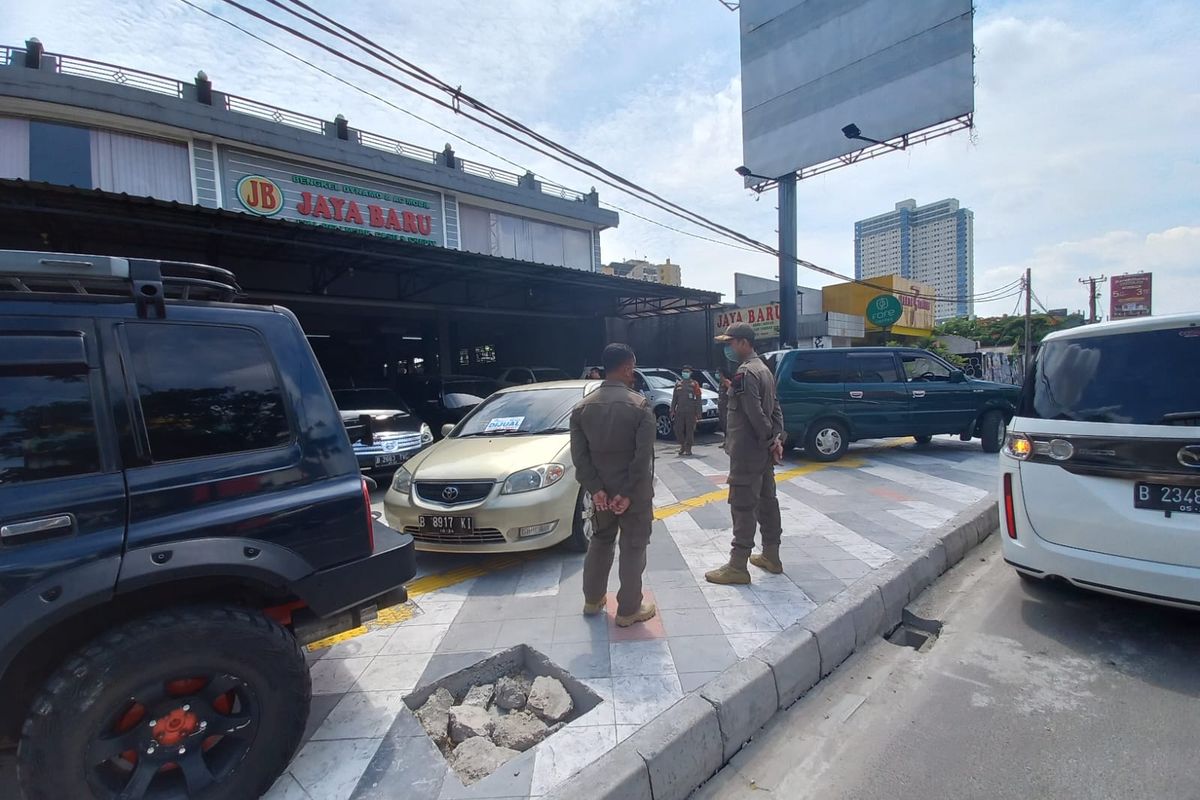 Satpol PP Kota Depok menindak pemilik showroom lantaran memarkirkan kendaraan mobil di atas trotoar Margonda pada Rabu (23/11/2022).