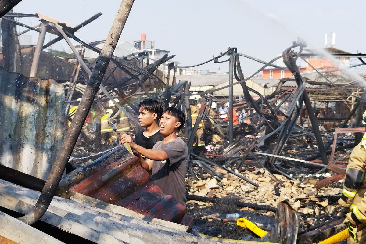 Dua orang warga membantu menyiramkan api ke sisa-sisa asap saat pendinginan kebakaran di Pasar Inpres Lontar, Kebon Melati, Tanah Abang, Jakarta Pusat, Rabu (9/8/2023). (KOMPAS.com/XENA OLIVIA)