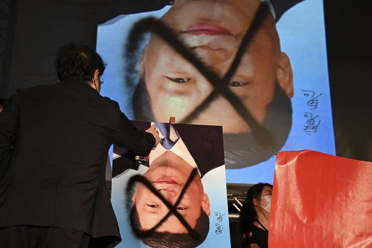 Demonstran menyemprotkan pilok untuk mencoret foto Presiden China Xi Jinping yang dibalik dalam demo anti-China di luar parlemen Taiwan di Taipei, 1 Oktober 2021. Penyebab kenapa China dan Taiwan bermusuhan bermula dari Perang Saudara China 1949.