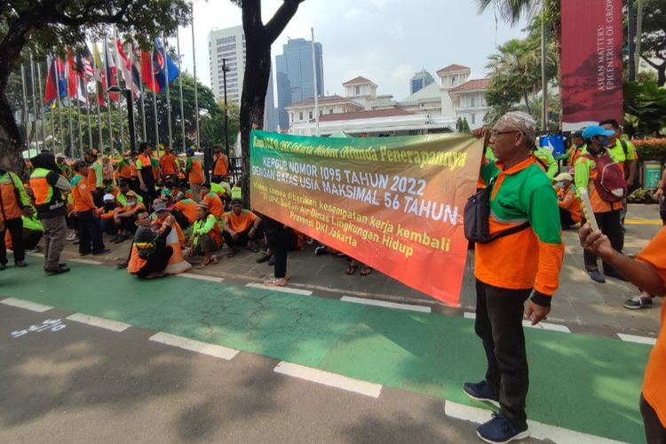 Sejumlah mantan penyedia jasa lainnya orang perorangan (PJLP) Unit Pelaksana Kebersihan (UPK) Badan Air Dinas Lingkungan Hidup (DLH) DKI Jakarta menggelar aksi unjuk rasa di depan Gedung Balai Kota, Gambir, Senin (13/3/2023).   Kedatangan sejumlah massa tersebut menuntut pertanggungjawaban Pemerintah Provinsi (Pemprov) DKI Jakarta soal pembatasan usia PJLP hingga 56 tahun.