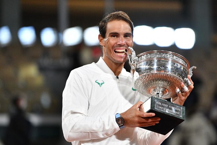 Petenis tunggal putra Spanyol, Rafael Nadal, menggigit Mousquetaires Cup (The Musketeers) saat seremoni kemenangannya pada laga final French Open 2020. Pada laga final yang berlangsung di lapangan Philippe Chatrier, Minggu (11/10/2020), Nadal mengalahkan Novak Djokovic.