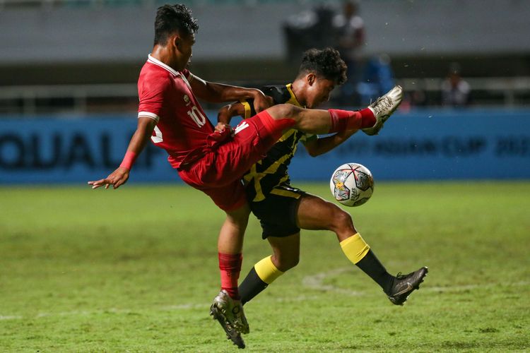 Pemain timnas U17 Indonesia Muhammad Nabil Asyura berebut bola dengan pemain timnas Malaysia Danish Darus pada laga Kualifikasi Piala Asia U17 2023 di Stadion Pakansari, Kabupaten Bogor, Minggu (9/10/2022).