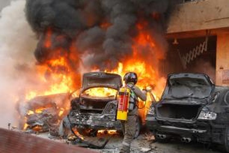 Seorang anggota pemadam kebakaran mencoba memadamkan api yang membakar sebuah mobil yang diduga menjadi sumber ledakan bom yang mengguncang kawasan Haret Hreik, Beirut, Lebanon, Selasa (21/1/2014). Kawasan ini merupakan salah satu basisi kelompok Hezbollah dan sudah beberapa kali menjadi sasaran serangan bom.
