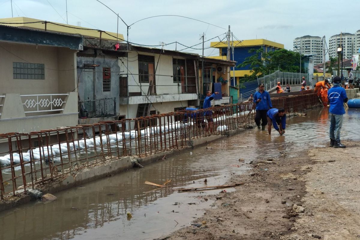 Petugas PPSU dan SDA bahu membahu menutup limpasan air dengan karung pasir di Penjaringan, Jakarta Utara Selasa (5/12/2017)