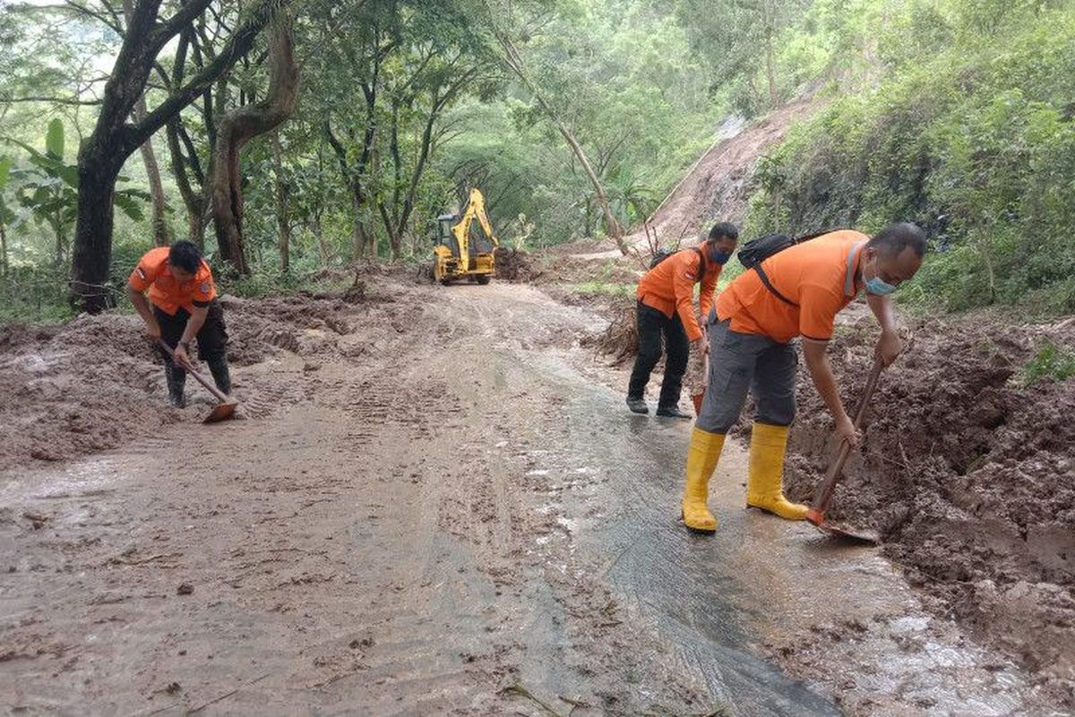 Petugas menangani material longsor yang menutup akses jalan lingkar Waduk Wonorejo, Tulungagung, Jumat (19/11/2021).