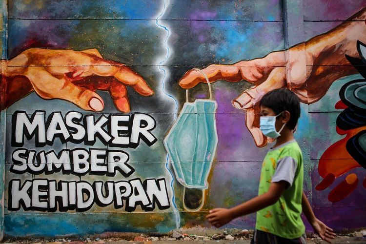 Seorang bocah melintas di depan mural tentang penggunaan masker di Kota Tangerang, Banten, Minggu (21/12/2020). Mural tersebut dibuat sebagai edukasi kepada masyarakat untuk selalu menggunakan masker guna mencegah penyebaran COVID-19. ANTARA FOTO/Fauzan/aww.