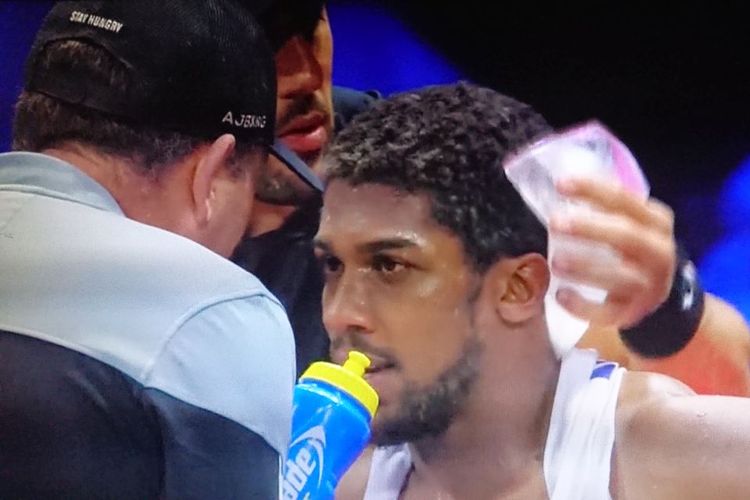 Petinju asal Inggris, Anthony Joshua, sedang menerima instruksi dari pelatihnya pada laga tinju kontra Andy Ruiz Jr di Diriyah Arena, Arab Saudi, Minggu (8/12/2019) dini hari WIB.