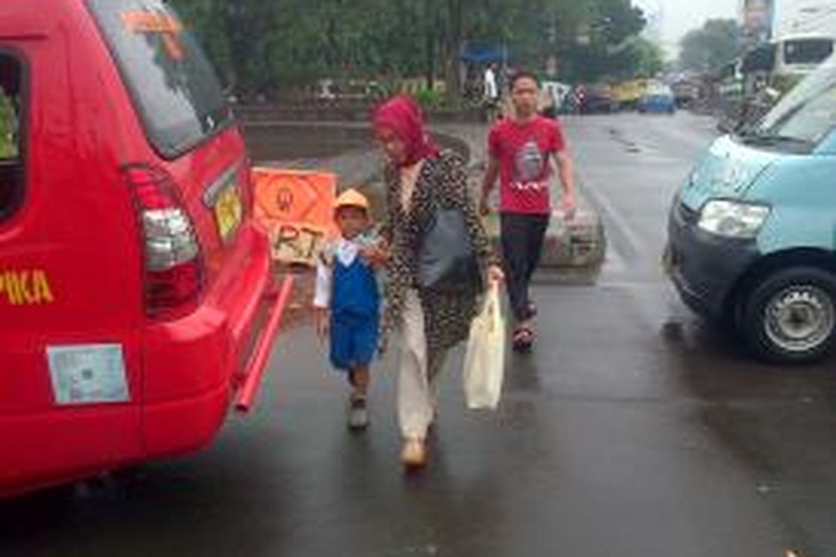 Asari salah satu pejalan kaki menyebrangi jalan di persimpangan Pasar Jumat, Lebak Bulus, Jakarta Selatan, Kamis (22/1/2015)