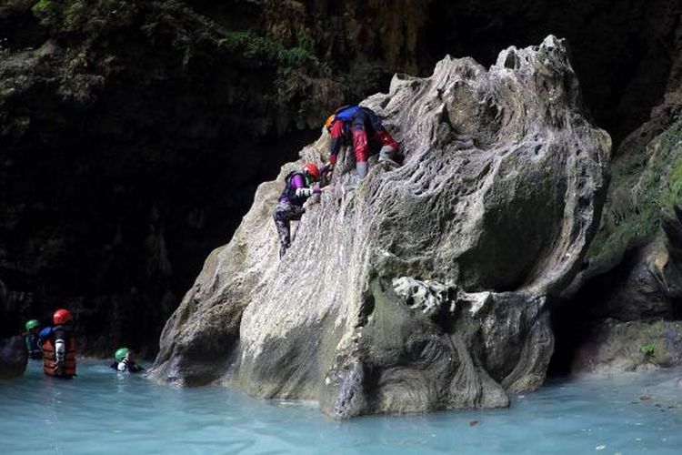 Beberapa peserta cave tubing berusaha memanjat salah satu batu yang terdapat di bagian Goa Kalisuci, Gunungkidul, DI Yogyakarta untuk berpose di goa yang eksotis tersebut.