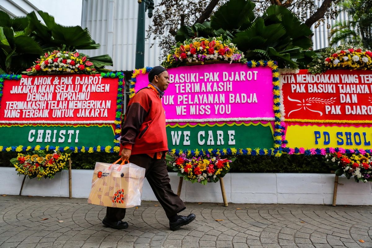 Warga melintas di antara karangan bunga yang ditujukan untuk Basuki Tjahaja Purnama atau Ahok dan Djarot Saiful Hidayat di kompleks Balai Kota DKI Jakarta, Senin (9/10/2017). Karangan bunga tersebut berisi ucapan terima kasih dari warga atas kepemimpinan Basuki dan Djarot selama berpasangan menjadi gubernur dan wakil gubernur DKI Jakarta.