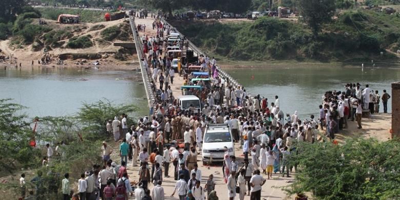 Polisi dan aparat pemerintah lain berkumpul di atas jembatan yang melintasi Sungai Sindh, setelah kepanikan yang membuat 115 orang peziarah Hindu tewas terinjak-injak atau tenggelam di sungai.
