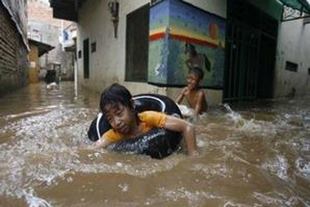 Ayu (depan) dan Mamat bermain air bah di RW 10, Kelurahan Bukit Duri, Kecamatan Tebet, Jakarta Selatan, Senin (3/11).