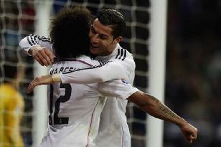 Penyerang Real Madrid, Cristiano Ronaldo (kanan), memeluk Marcelo yang memberikan assist sehingga dia mencetak gol ketiga Madrid saat menang 3-0 atas Celta Vigo dalam lanjutan Primera Division di Santiago Bernabeu, Sabtu (6/12/2014). Ronaldo membuat hat-trick dalam laga ini.