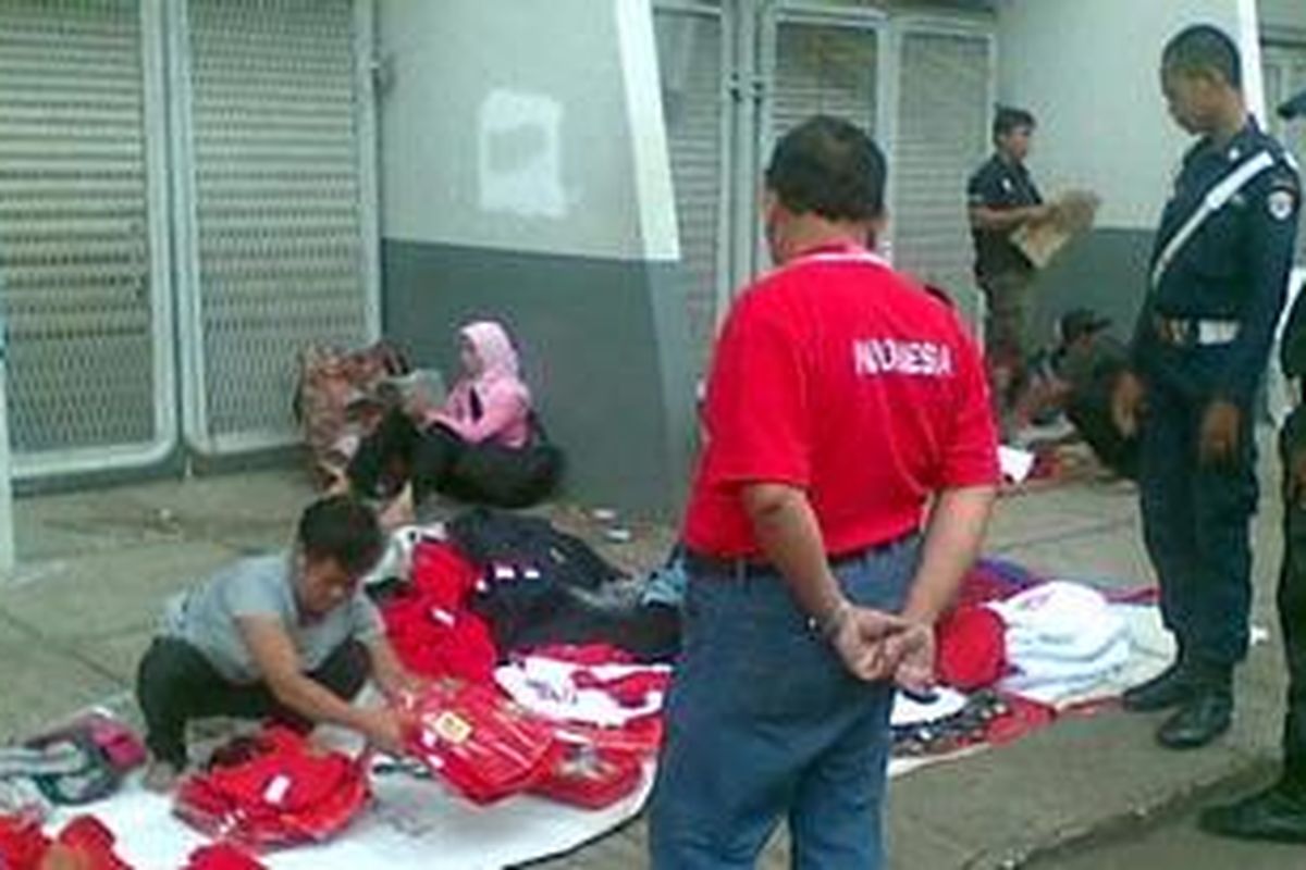 Salah seorang pedagang mengemas barang dagangannya di hadapan sejumlah petugas keamanan, Minggu (26/12/2010) di sekitar Pintu Merah Stadion Utama Gelora Bung Karno, Jakarta.