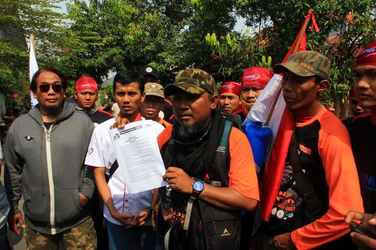 Ade Kenzo menunjukkan sebuah kertas yang berisi 19 butir tuntutan yang dikeluhankan warga terkait sistem pelayanan kesehatan, Selasa (10/10/2017). Dia sudah berjalan kaki selama 21 hari dari Tugu Pahlawan Surabaya ke Cirebon, dan akan melanjutkan perjalanan ke Jakarta untuk menemui Presiden Joko Widodo.