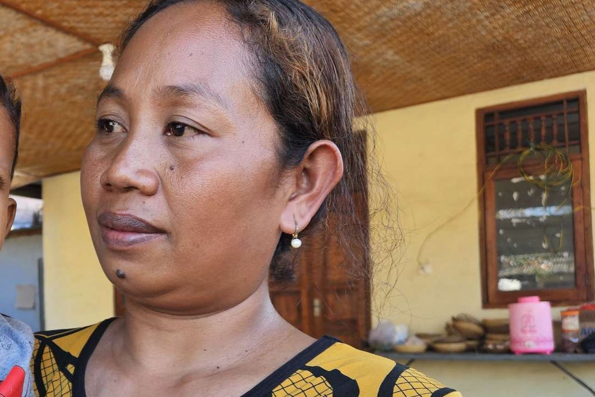 Kadek Sudiartini (38) menggendong putra bungsunya, Kamis (10/7/2025) di Buleleng, Bali. Sudiartini merupakan istri Putu Mertayasa (43), salah satu korban tenggelamnya KMP Tunu Pratama Jaya.