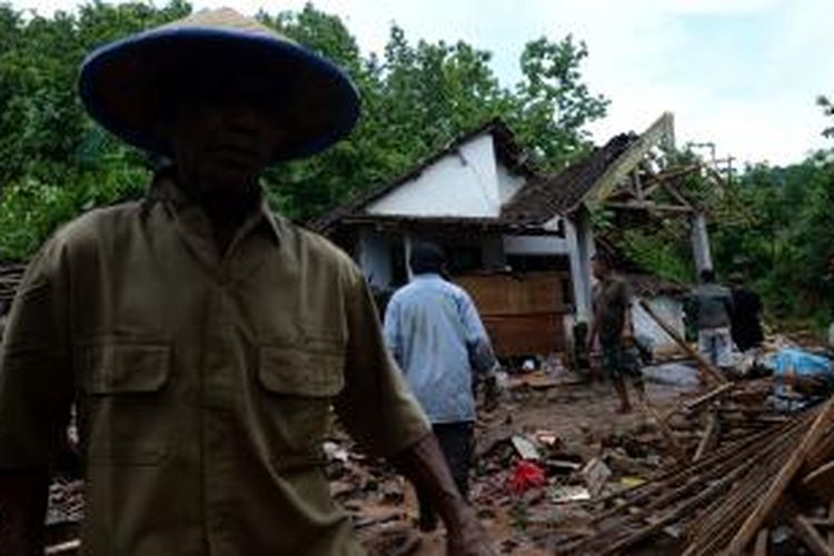 Warga melintas di dekat salah satu rumah yang rusak karena tanah longsor di Dusun Kopen, Desa Ngrimbi, Kecamatan Bareng, Jombang, Selasa (28/1/2014). Petugas berhasil mengevakuasi 7 jenazah dari perkiraan 14 warga yang tertimbun longsoran. SURYA/AHMAD ZAIMUL HAQ