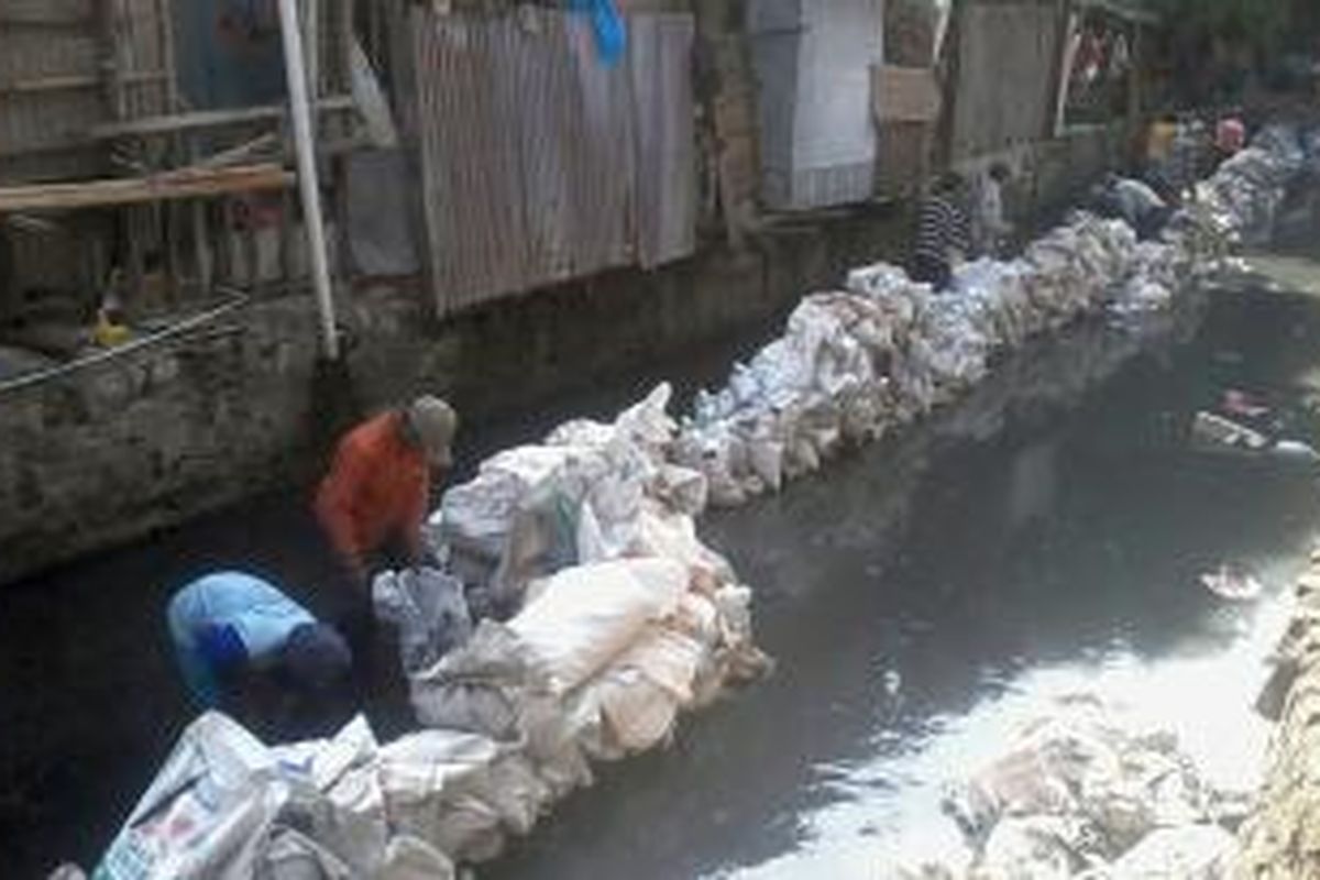 Pekerja mengisi karung-karung plastik dengan endapan di Sungai Krukut, Jakarta Pusat, Senin (26/8/2013).