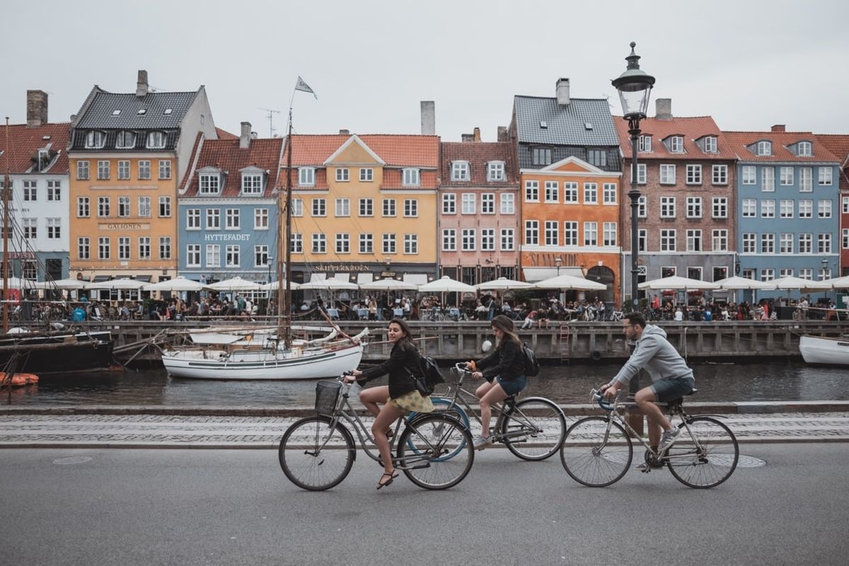 Turis sedang bersepeda di Nyhavn, Kopenhagen, Denmark.